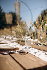 Close-up of an elegant rustic wedding table setting with white plates, woven placemats, and simple...