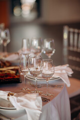 Close-up of an elegant wedding table setting with white plates, white napkins, and various wine...