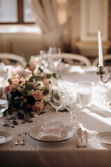 Elegant wedding table setting with a white tablecloth, pink napkins, simple floral centerpiece, and...