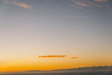 The sky is a beautiful orange color, and the ocean is calm. The scene is peaceful and serene