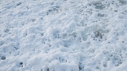 Obraz premium Vibrant ocean foam swirls in a captivating close up forming hypnotic patterns as waves recede