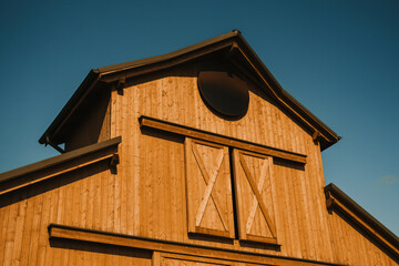 A beautifully designed rustic barn made of aged wooden planks set against a vibrant, clear blue sky above