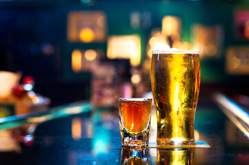 Pint of Beer and shot of Whiskey on bar at night with colorful lights