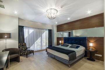 A luxurious bedroom with a modern interior design. A bed against the wall with mirror inserts,...