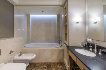 Stylish design of the bathroom, decorated with beige tiles, with elegant furniture and retro style faucets.