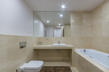 Elegant design of the bathroom decorated with beige tiles. Large mirror over the sink, stylish interior elements.