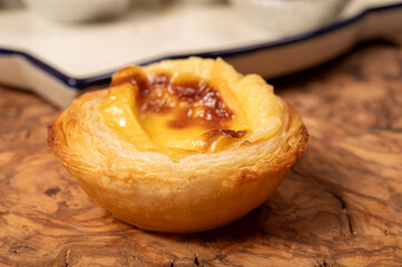 Portugal's traditional sweet dessert Pastel de nata egg custard tart pastry in cup close up on wooden background