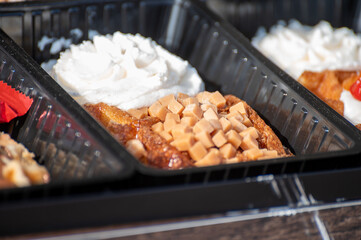 Variety of fresh baked waffles richly decorated with different toppings, sweet sweets, chocolate, cream, fruit and berries, jelly sweets in bakery with confectionery shop, old Volendam, Dutch sweets