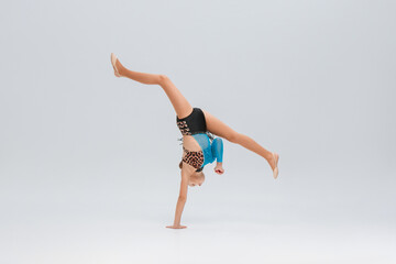gymnast executes a flawless horizontal split in a handstand, balancing power and grace. Her outfit adds a dynamic visual appeal. Athleticism and grace captured in one frame, somersault