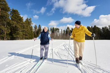 European couple around 50 years old cross country skiing on snowy field.