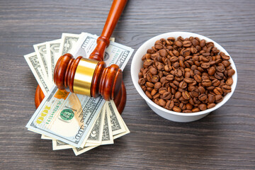 A wooden gavel rests on a stack of U.S. $100 bills, symbolizing justice or legal costs, beside a...