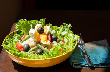 Plate of keto salad with fork and napkin and black background
