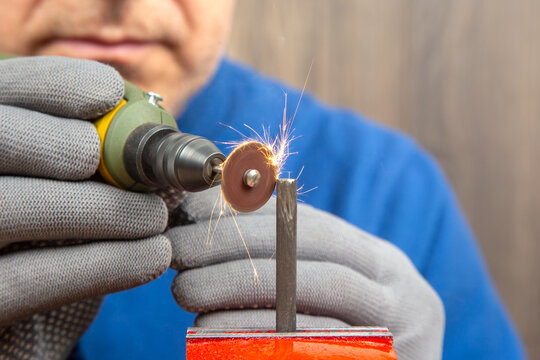 Male locksmith worker processes metal with engraving drill cutting. The work of the dremel engraving electric tool. Industrial metal processing industry