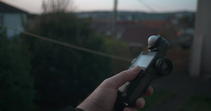 Photographer using light meter to measure light level outdoors