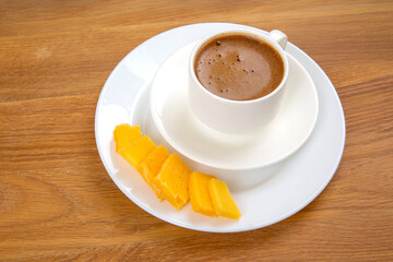 A top-down view of a white cup filled with rich espresso, featuring a frothy top, placed on a...