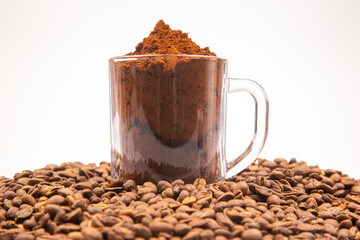 Vibrant image of a glass mug brimming with finely ground coffee, set against a backdrop of roasted coffee beans, highlighting the essence of coffee preparation.