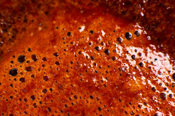 Macro close-up of frothy coffee crema with golden-brown bubbles, showcasing rich texture and reflective surfaces. Perfect for coffee lovers, beverage ads, or food photography