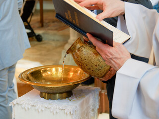 Eau bénite versée lors d’un baptême religieux dans une église – symbole de purification et...
