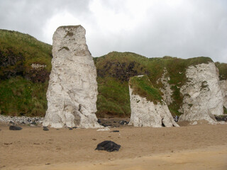 A rocky cliff with a white rock on the beach