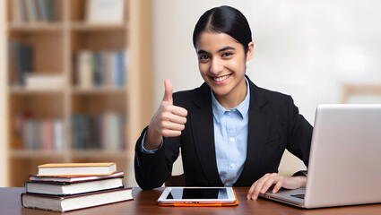 Fototapeta premium Successful Study: Girl with Thumbs Up at Her Workspace. Smiling Young Woman Giving Thumbs Up While Studying. 