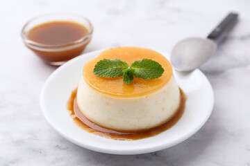 Tasty pudding with caramel sauce served on white marble table, closeup