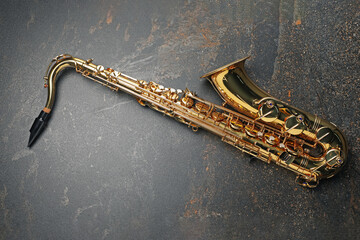 Jazz. One saxophone on black textured table, top view