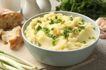 Delicious mashed potato with green onions served on grey table, closeup