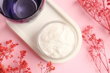 Collagen powder in bowl, glass and gypsophila branches on pink background, flat lay