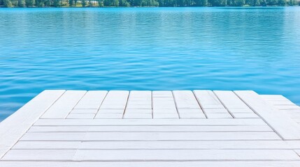 Obraz premium A white wooden dock extends over a tranquil blue lake. The docks planks are neatly arranged. The background showcases a serene lake with a distant shoreline. The image is high-quality, with bright na