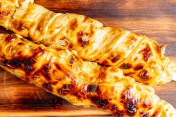Freshly baked pastry rolls with golden crust on wooden board