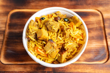 Flavorful rice dish with tender meat on wooden table