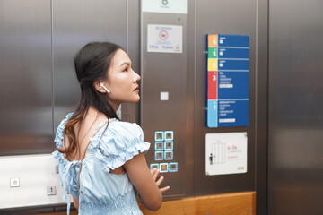 young asian woman pressing elevator button