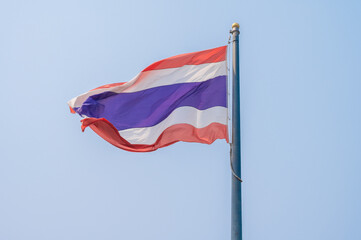 A Thailand national flag blowing by wind against the sky.