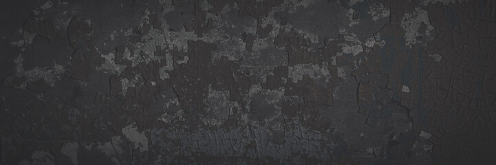 Dark wide panoramic background. Peeling paint on a concrete wall. Faded dark texture of old cracked flaking paint. Weathered rough painted surface with patterns of cracks. Shaded background for design