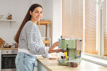 Beautiful young happy woman with modern coffee machine in kitchen