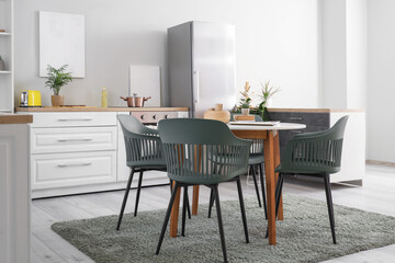 Stylish interior of modern kitchen with fridge, counter and dining table
