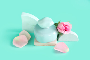 Decorative podiums with bottle of perfume and beautiful pink rose on turquoise background