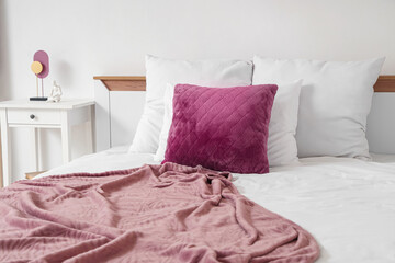 Stylish purple blanket with pillows on bed in modern bedroom