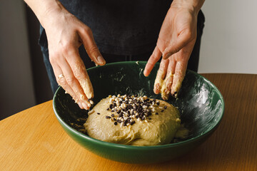 A woman in casual attire prepares dough for baking. She looks pleased and focused, enjoying the baking process in a light-filled kitchen.