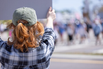 An anonymous woman holds up a sign at a the April 5, 2025, Hands Off protest against the Trump...