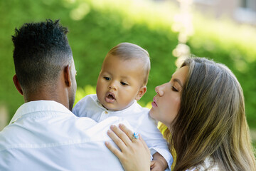 Multiethnic parents Biracial baby in park. Multiracial couple outdoor portrait. Biracial baby child with parents in backyard. Diverse family. African american father mother with baby, family portrait.