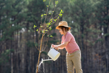 Kid with shovel in garden. Child planting tree. Little gardener with watering can. Spring garden...