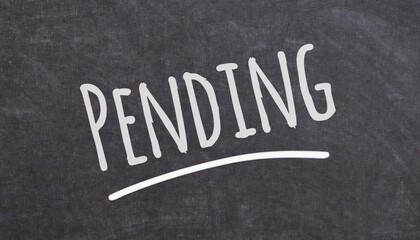 Obraz premium Handwritten pending label on black board