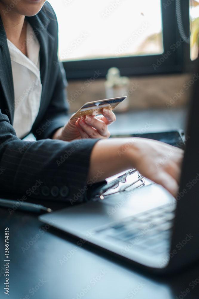 Poster close-up of a business professional holding a credit card while using a laptop, emphasizing online t