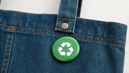 Conceptual image for World Environment Day. Green recycle badge pinned on denim tote bag promoting eco friendly lifestyle.