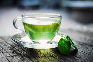 Steaming mint tea brewing in glass cup on rustic wooden table