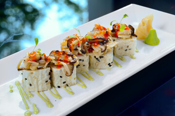 This image showcases an elegant plate of sushi rolls, artfully arranged on a rectangular white...