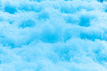 Blue water with ripples on the surface. Defocus blurred transparent blue colored clear calm water surface texture with splashes and bubbles. Water waves with shining pattern texture background.