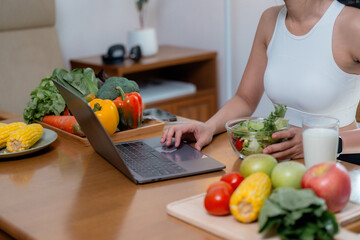 Nutritionist working on laptop with fresh vegetables and salad