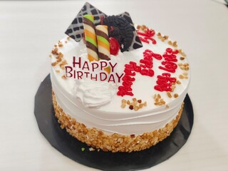 Birthday Cake with White Cream, Chocolate Toppings, and Happy Birthday Decoration